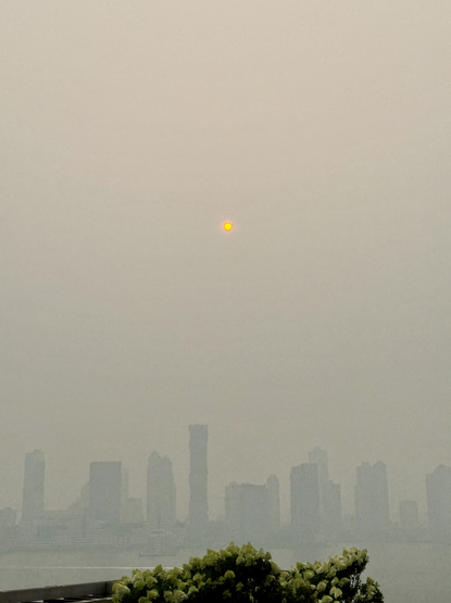 A photo of the sun setting over the Hudson River through smoke haze